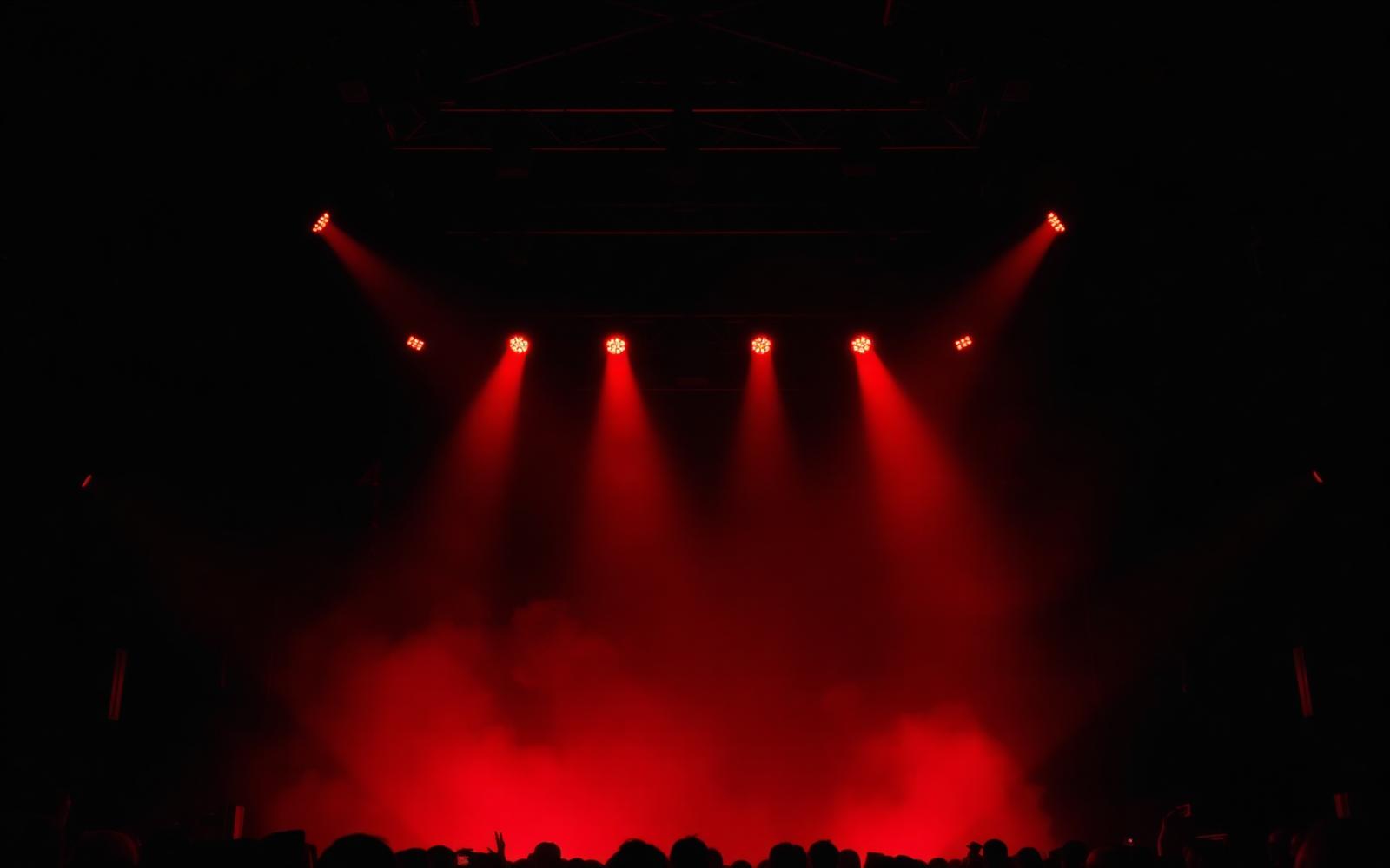 Dark concert stage with dramatic crimson stage lights and haze — a media.Xchange event moment